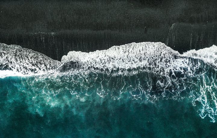 aerial photo of body of water crashing into shore